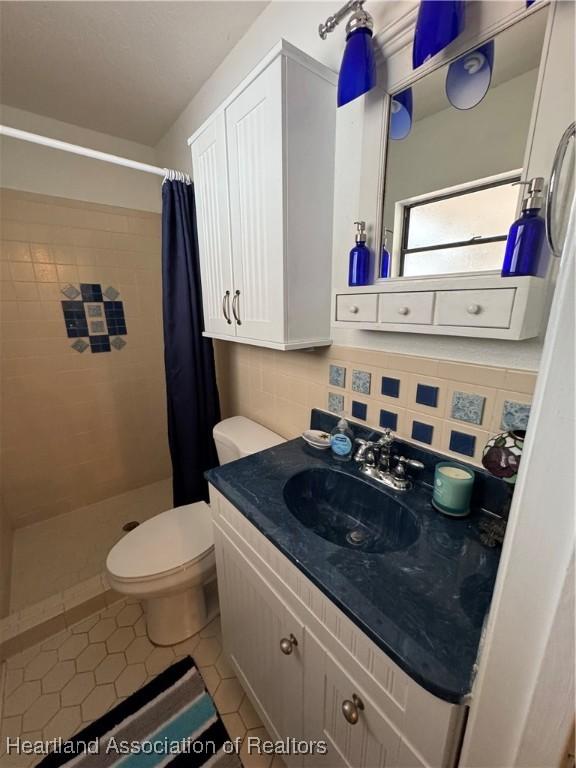 full bathroom featuring toilet, decorative backsplash, a shower stall, vanity, and tile patterned floors