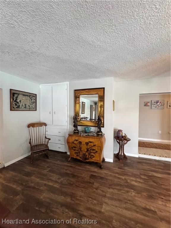 sitting room featuring a textured ceiling, baseboards, and wood finished floors