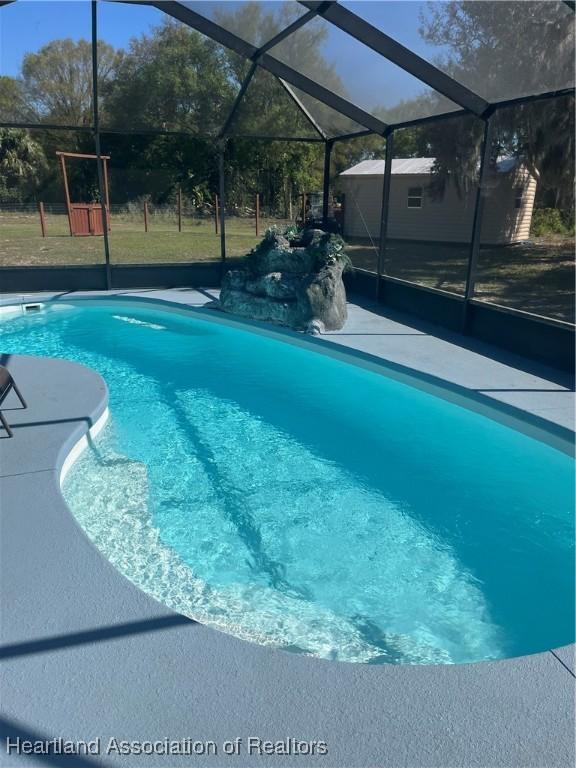 pool featuring a lanai, a patio area, and a lawn