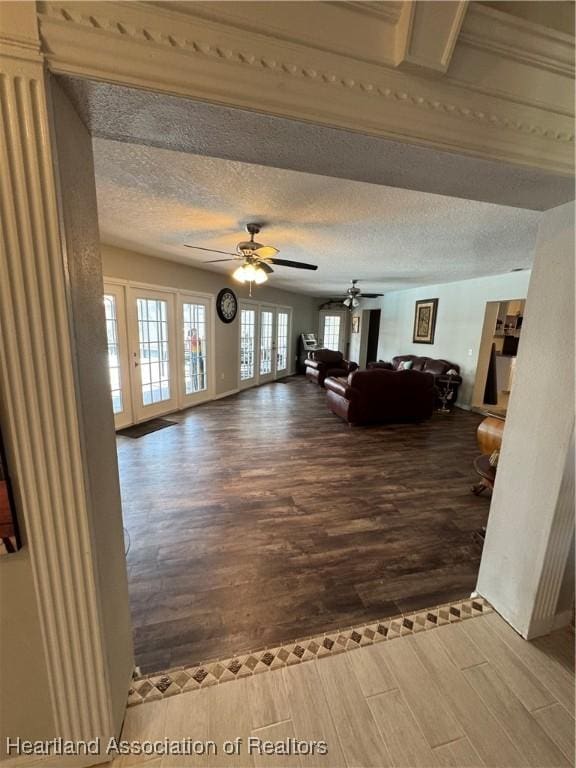 living room featuring ceiling fan, french doors, a textured ceiling, and wood finished floors