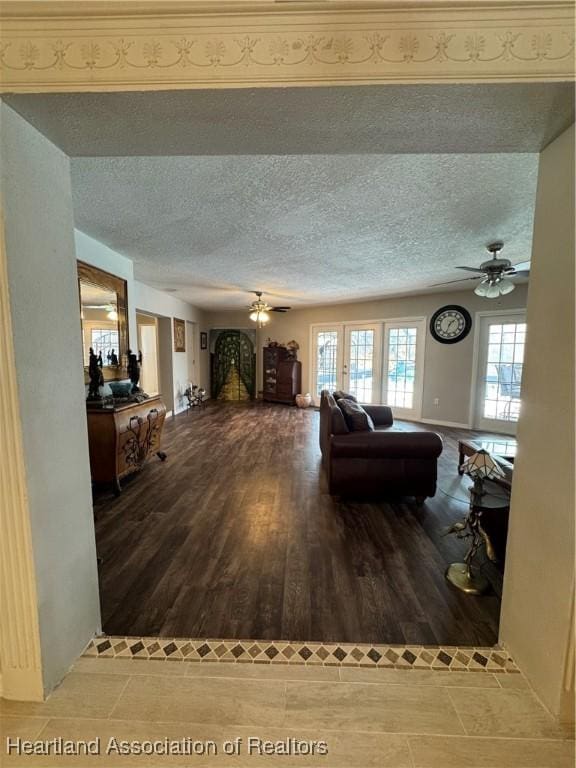 living room featuring ceiling fan, a textured ceiling, and wood finished floors