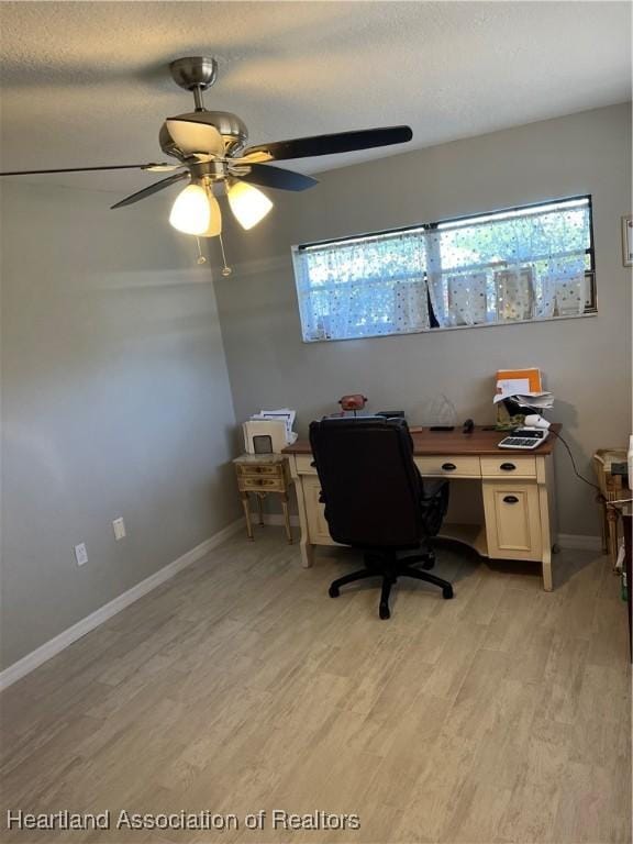 home office with light wood-type flooring, plenty of natural light, a textured ceiling, and baseboards