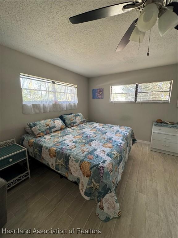 bedroom with wood tiled floor, ceiling fan, and a textured ceiling