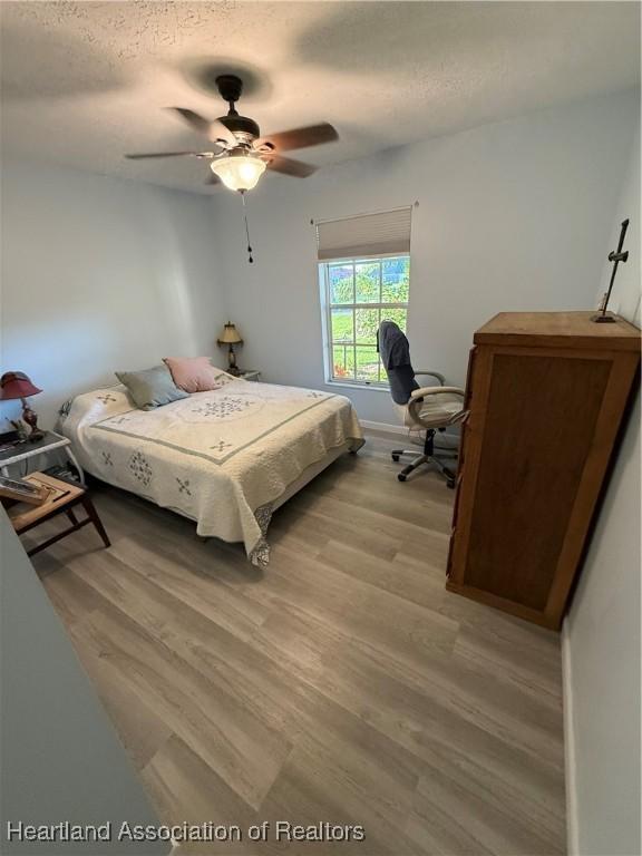 100 Daisy Ln, Lake Placid, FL 33852 - bedroom featuring light wood finished floors, a textured ceiling, and ceiling fan
