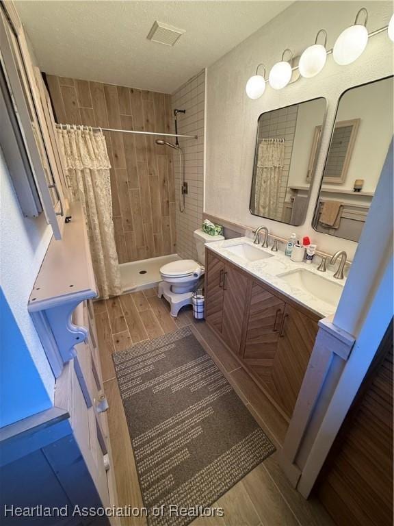 100 Daisy Ln, Lake Placid, FL 33852 - bathroom featuring wood finished floors, tiled shower, double vanity, and toilet