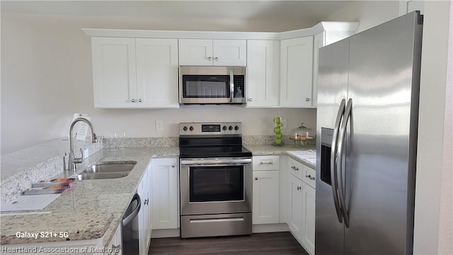 kitchen with light stone countertops, sink, dark hardwood / wood-style flooring, white cabinets, and appliances with stainless steel finishes