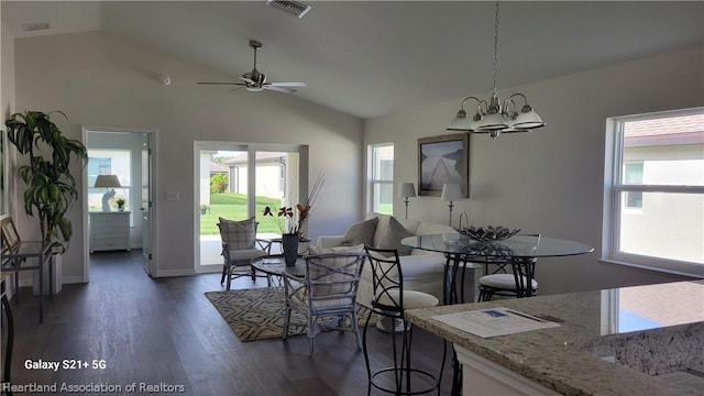 dining room featuring ceiling fan with notable chandelier, vaulted ceiling, and dark wood-type flooring