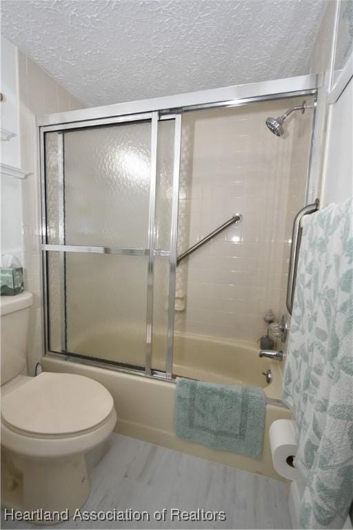bathroom featuring enclosed tub / shower combo, a textured ceiling, and toilet