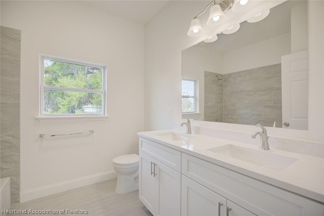 bathroom with vanity, toilet, and tiled shower