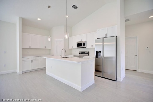 kitchen with pendant lighting, sink, an island with sink, white cabinetry, and stainless steel appliances