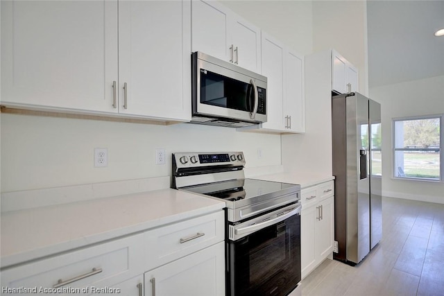 kitchen with white cabinetry, stainless steel appliances, and light hardwood / wood-style flooring