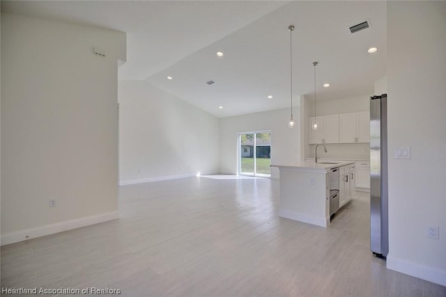 kitchen with a kitchen island with sink, white cabinets, sink, vaulted ceiling, and decorative light fixtures