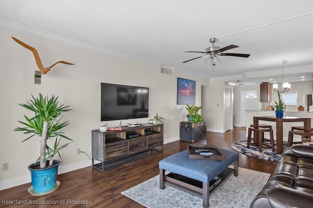 living room with dark wood-type flooring, ceiling fan with notable chandelier, and ornamental molding