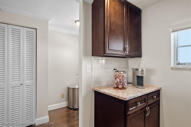 kitchen featuring dark brown cabinets, dark hardwood / wood-style flooring, ornamental molding, and backsplash