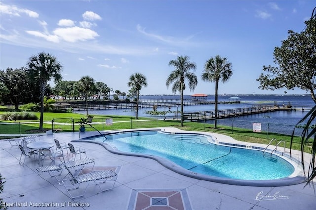 view of pool featuring a patio area, a water view, and a yard