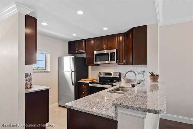 kitchen with kitchen peninsula, appliances with stainless steel finishes, backsplash, light stone counters, and sink