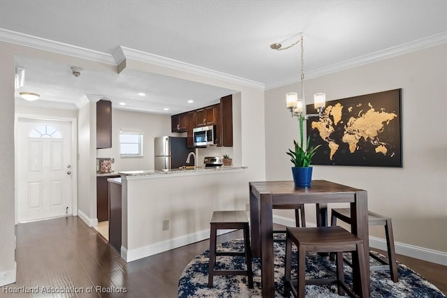 dining space with sink, an inviting chandelier, dark hardwood / wood-style floors, and ornamental molding