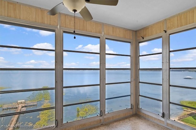 unfurnished sunroom with ceiling fan and a water view