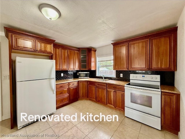 kitchen featuring light countertops, white appliances, backsplash, and glass insert cabinets