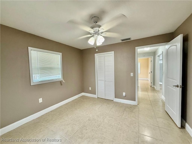 unfurnished bedroom with baseboards, visible vents, ceiling fan, a closet, and light tile patterned flooring