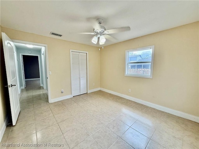 unfurnished bedroom with light tile patterned floors, a ceiling fan, visible vents, baseboards, and a closet