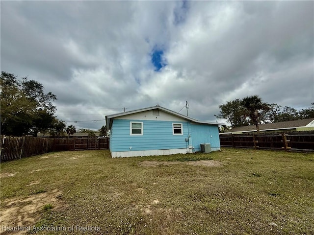 back of house featuring a yard, central AC unit, and a fenced backyard