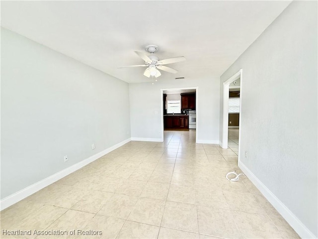 spare room with light tile patterned floors, ceiling fan, visible vents, and baseboards