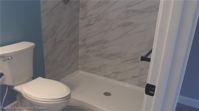 bathroom featuring toilet and a tile shower