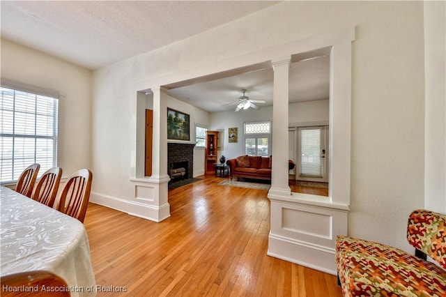 2220 Lakeview Dr, Sebring, FL 33870 - dining space with a fireplace, a ceiling fan, baseboards, light wood finished floors, and decorative columns