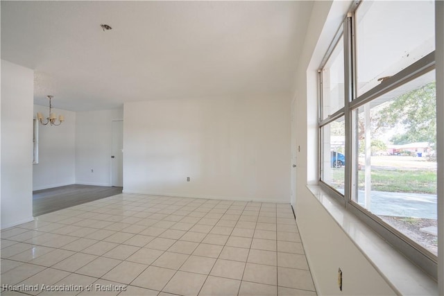 unfurnished room featuring baseboards, light tile patterned flooring, and a chandelier