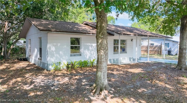 rear view of house with fence and roof with shingles