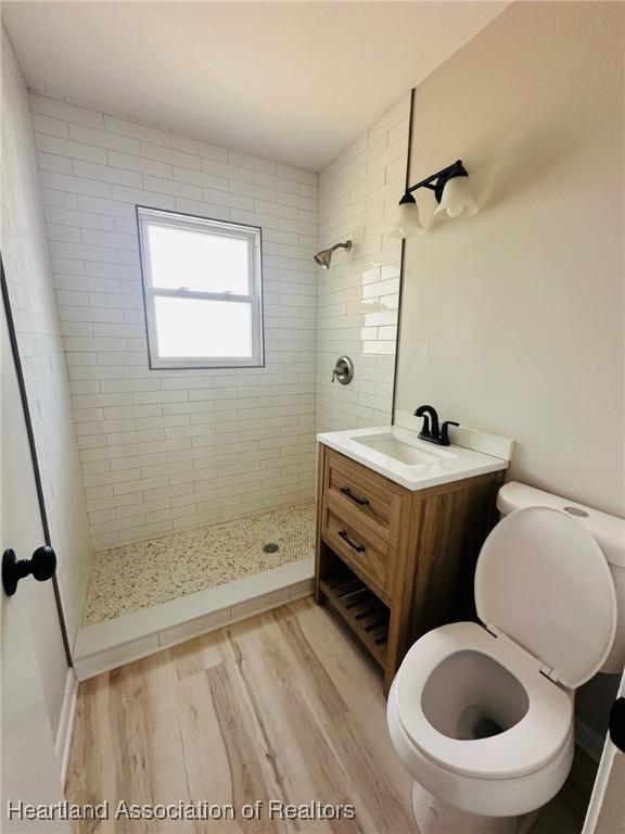 602 Wilhite St, Avon Park, FL 33825 - bathroom with a tile shower, toilet, vanity, and wood finished floors