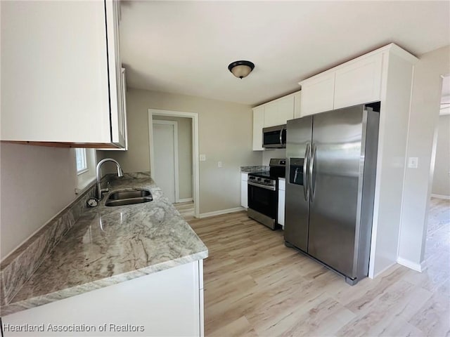 602 Wilhite St, Avon Park, FL 33825 - kitchen featuring light wood finished floors, a sink, white cabinetry, light stone counters, and appliances with stainless steel finishes