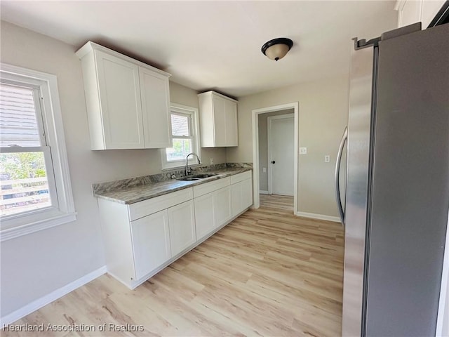 602 Wilhite St, Avon Park, FL 33825 - kitchen featuring white cabinets, a sink, freestanding refrigerator, light wood-type flooring, and baseboards
