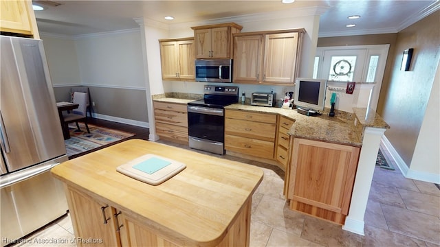 kitchen with kitchen peninsula, appliances with stainless steel finishes, light stone countertops, ornamental molding, and light brown cabinets