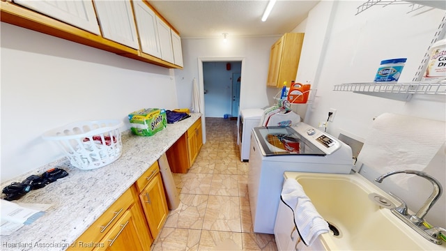 washroom with cabinets, washing machine and dryer, and sink