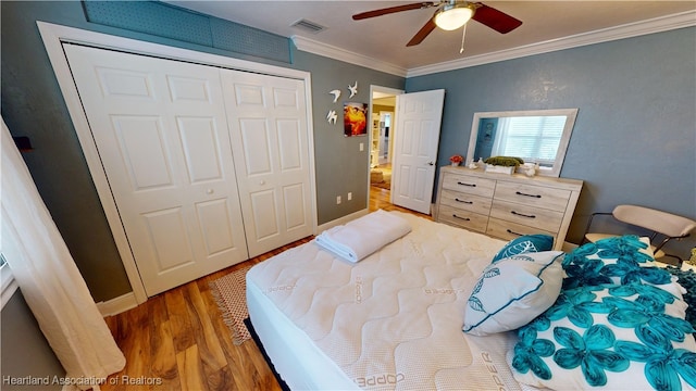 bedroom with hardwood / wood-style flooring, ceiling fan, ornamental molding, and a closet