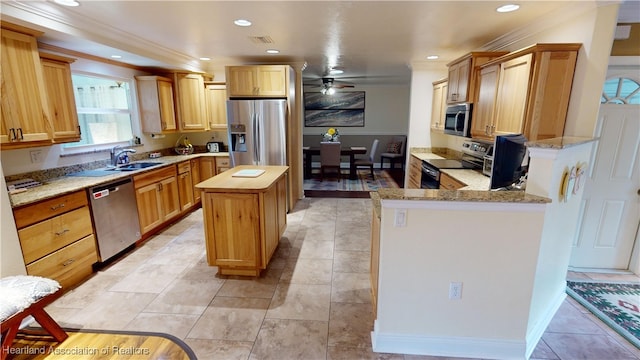 kitchen featuring ceiling fan, a center island, light stone countertops, appliances with stainless steel finishes, and ornamental molding