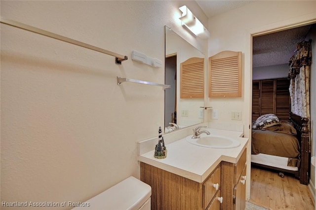 bathroom featuring hardwood / wood-style flooring, vanity, a textured ceiling, and toilet