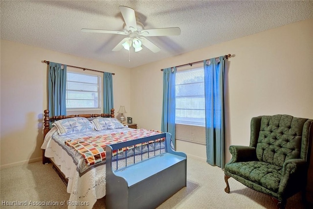 bedroom with ceiling fan, light carpet, and a textured ceiling