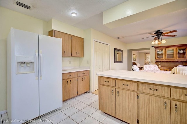 kitchen with white fridge with ice dispenser, light tile patterned floors, ceiling fan, light brown cabinets, and a textured ceiling