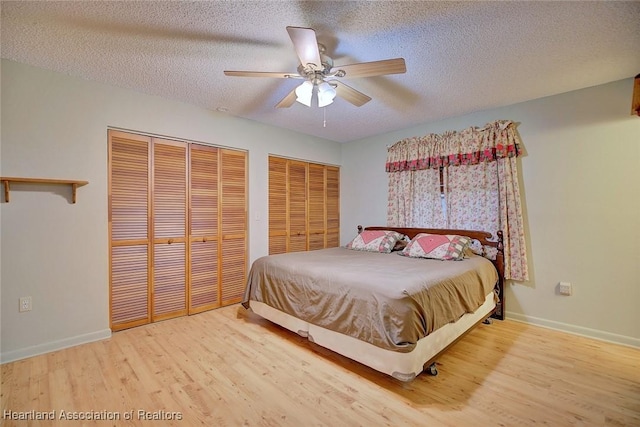 bedroom featuring hardwood / wood-style floors, a textured ceiling, ceiling fan, and two closets