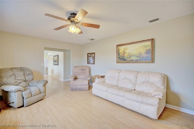 living room with hardwood / wood-style flooring, ceiling fan, and a textured ceiling