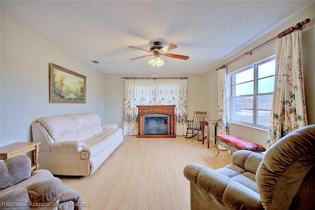 living room featuring ceiling fan, light hardwood / wood-style floors, and a textured ceiling