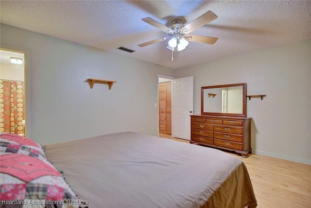 bedroom with a textured ceiling, light hardwood / wood-style flooring, and ceiling fan