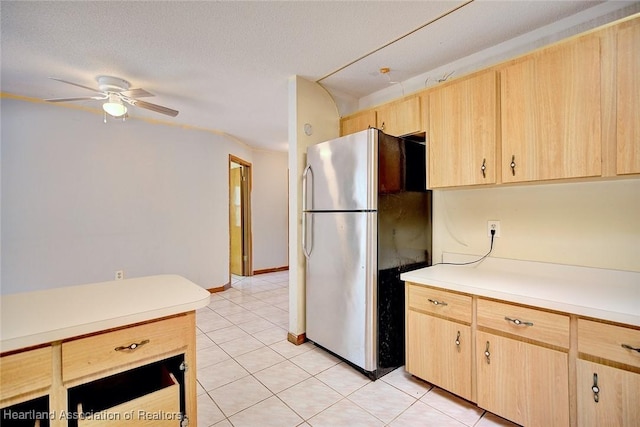kitchen with ceiling fan, light countertops, freestanding refrigerator, light brown cabinets, and light tile patterned flooring
