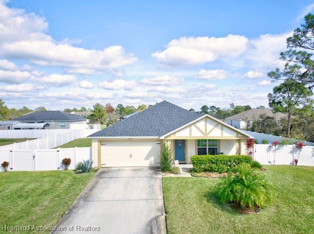 view of front of house featuring a garage, concrete driveway, fence, and a front lawn