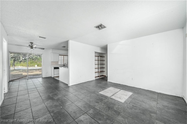 unfurnished living room with a textured ceiling and ceiling fan