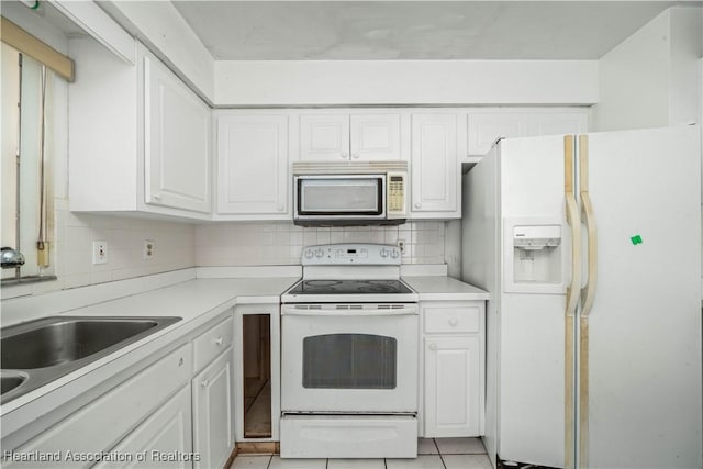 kitchen featuring white appliances, sink, light tile patterned floors, tasteful backsplash, and white cabinetry