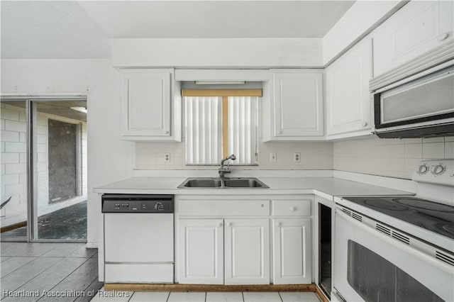 kitchen with white cabinetry, sink, white appliances, decorative backsplash, and light tile patterned floors